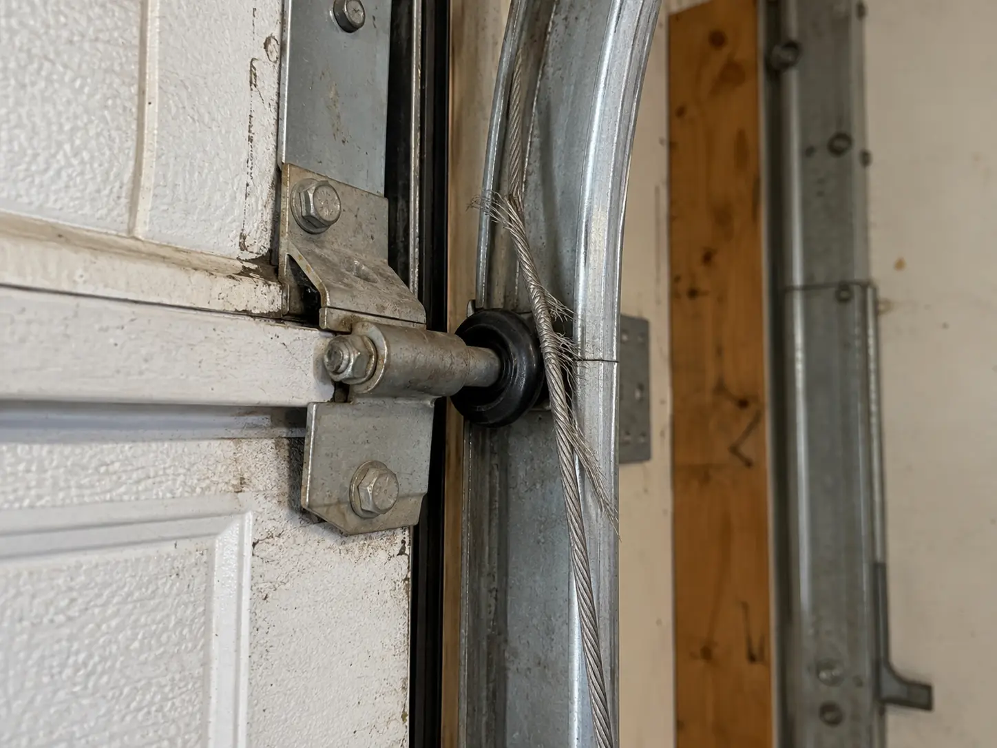 Frayed garage door cable beside a door track